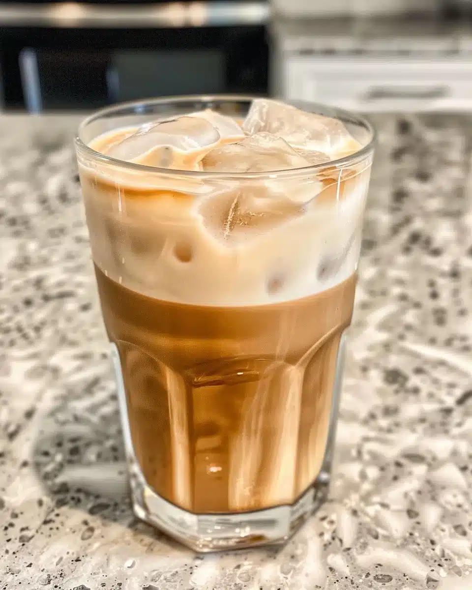 A delicious glass of banana milk cold brew topped with frothy foam.