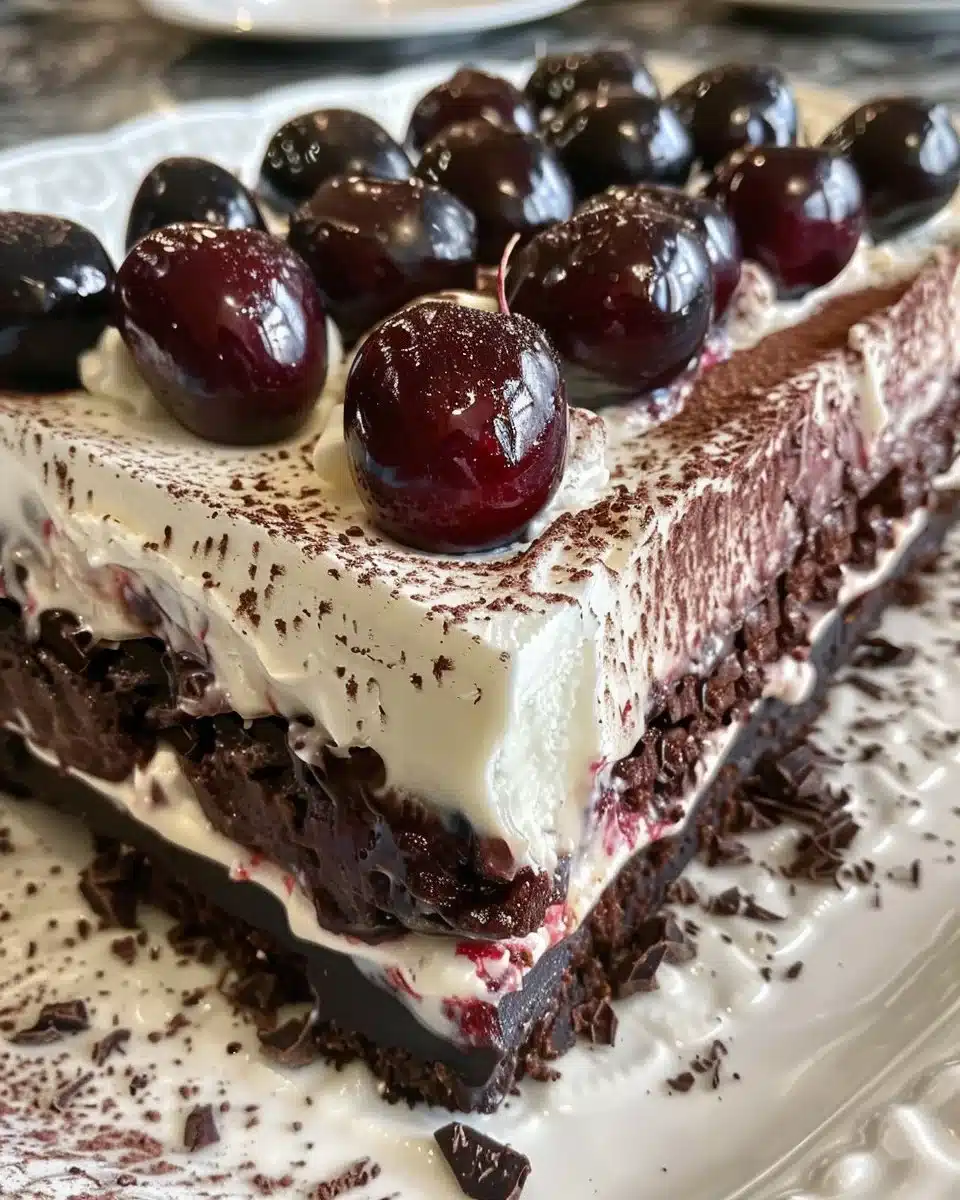 Vertical Black Forest Swiss Roll Cake with whipped cream and cherries on top.